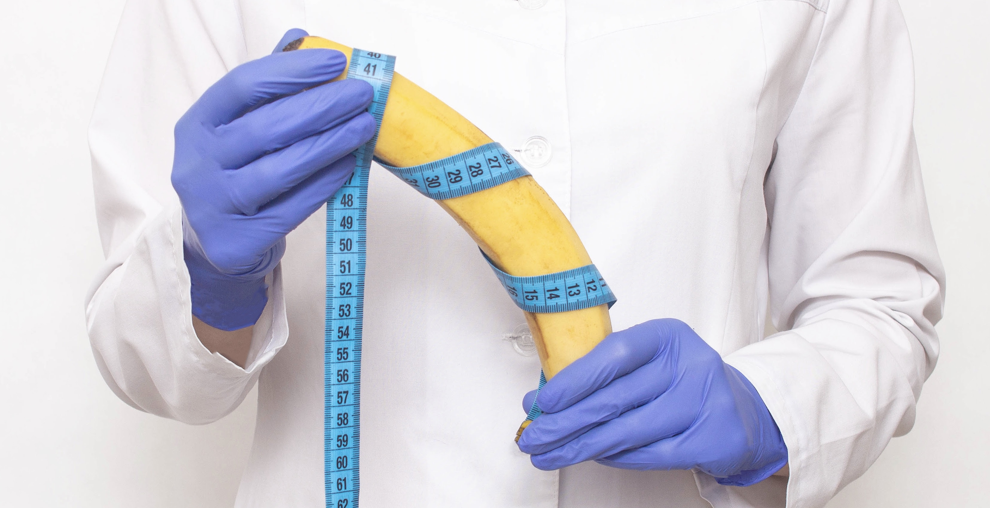 Dr. plastic hiururg holds a banana in his hands. The concept of plastic surgery for penis enlargement, phalloplasty
